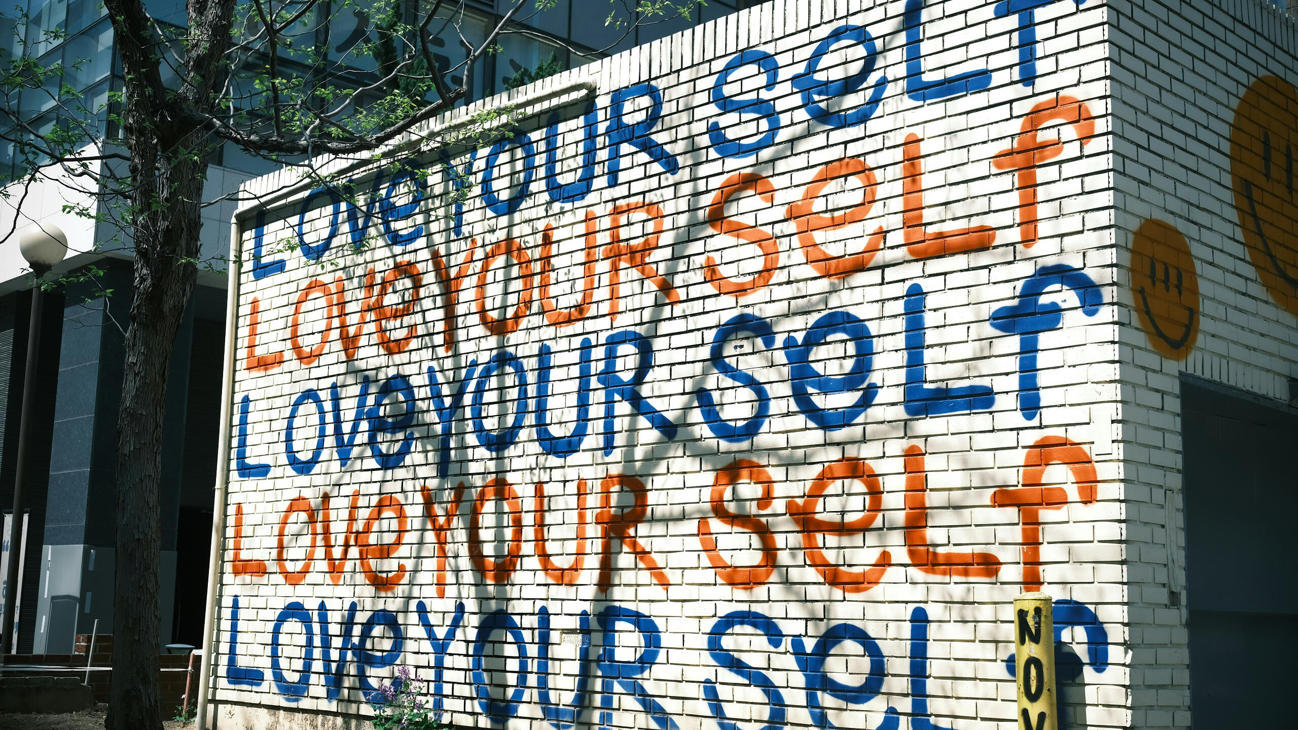 A painted wall that reads over and over again , "Love Your Self"